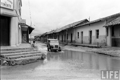         Niño mirando un jeep cruzar el charco de agua formado en la calle Pari esquina Independencia – fotografía 1 de 3
