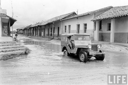         Niño mirando un jeep cruzar el charco de agua formado en la calle Pari esquina Independencia – fotografía 3 de 3
