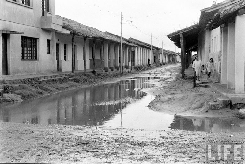         Mujer y niña caminando y sosteniendo una canasta en la vereda de la calle Pari esquina Independencia
